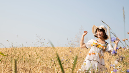Happy cute girl in a wheat field with background.の写真素材