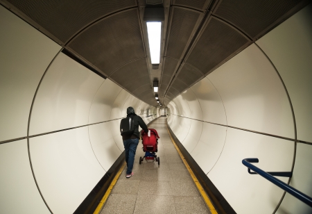 A woman pushing a pram in a subway tunnelの写真素材