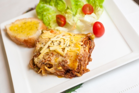 Lasagne on a plate serve with lettuce and garlic breadの写真素材