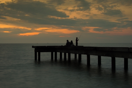 Silhouette of an Unknown Boy Fishin on a jetty during a sunset の写真素材