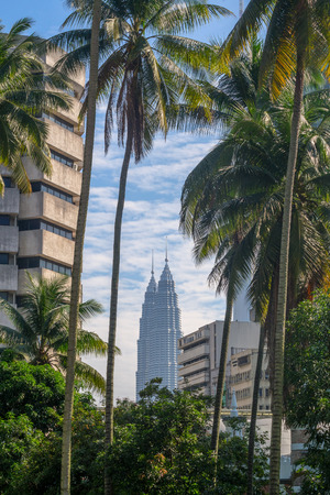 Petrowas Twin Towers in between buildings and coconut treesのeditorial素材