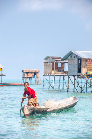 Sea Gypsy Woman paddling her sampan with her kids.のeditorial素材