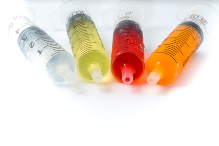 Syringe with colorful kids medicine syrup on white backgroundの写真素材