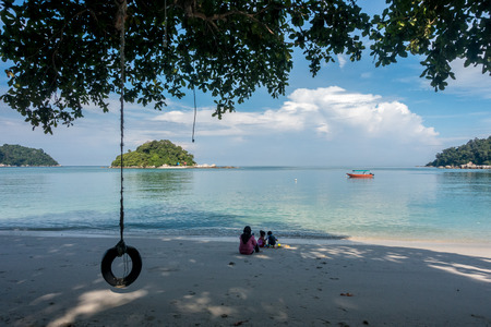 Silhouette of a tyre/tire swing at a beach overlooking a beautiful sea water.の写真素材