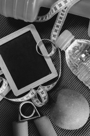 Lay Flat - Dumbbell, Measuring Tape, Hand Grip, Mineral Water, Fresh Apple & Blank Blackboard for Motivational Quotes/Words on red background - Fitness Conceptの写真素材