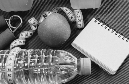 Lay Flat - Dumbbell, Measuring Tape, Hand Grip, Mineral Water, Fresh Apple & Blank Notebook for Motivational Quotes/Words on red background - Fitness Conceptの写真素材