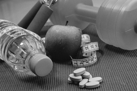 Lay Flat - Dumbbell, Measuring Tape, Hand Grip, Mineral Water, Fresh Apple & Vitamins on red background -  Fitness Conceptの写真素材