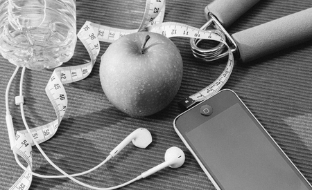 Lay Flat - Dumbbell, Measuring Tape, Hand Grip,  Fresh green apple, Mineral Water, Smartphone & Earphone on red background - Fitness Conceptの写真素材