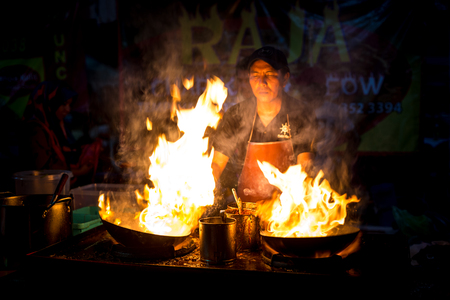 Malaysia Circa 2017 - A Chef cooking  Char Kuey Teow, a spicy rice noodle dish with prawns in his cast iron wok at his roadside stall. Big fire from his wok attracting buyers. Motion blur to show movementのeditorial素材