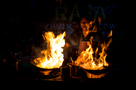 Malaysia Circa 2017 - A Chef cooking  Char Kuey Teow, a spicy rice noodle dish with prawns in his cast iron wok at his roadside stall. Big fire from his wok attracting buyers. Motion blur to show movementのeditorial素材