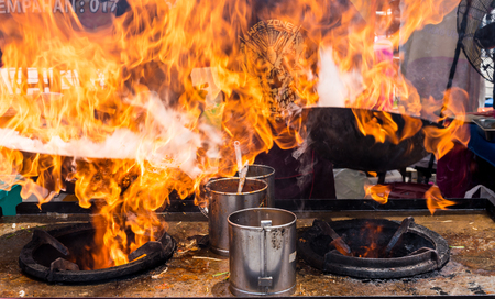 Malaysia Circa 2017 - A Chef cooking Char Kuey Teow, a spicy rice noodle dish with prawns in his flaming cast iron wok at his roadside stall. Motion blur to show movementのeditorial素材