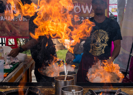 Malaysia Circa 2017 - A Chef cooking Char Kuey Teow, a spicy rice noodle dish with prawns in his flaming cast iron wok at his roadside stall. Motion blur to show movementのeditorial素材