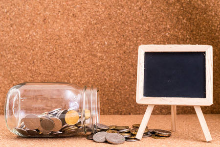 Finance Concept - A jar of coins and a blank blackboard for text. Wood Background. Shallow depth of...