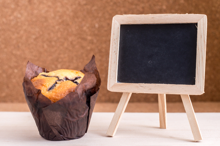 Blueberry Muffin and blank blackboard for text. Wood background. Shallow depth of field.の写真素材