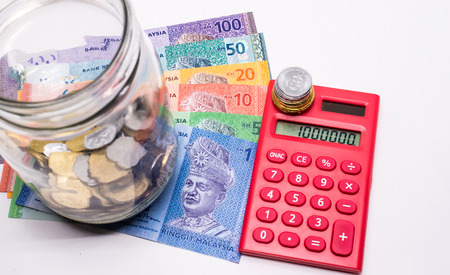 Jar of Malaysia Coins, Ringgit banknotes, red calculator. White background.  Savings concept....