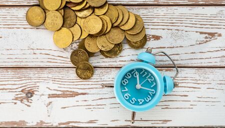 Savings for the future. Malaysia coins and clock on wooden background. Shallow depth of field