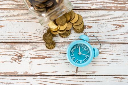 Savings for the future. Malaysia coins and clock on wooden background. Shallow depth of field