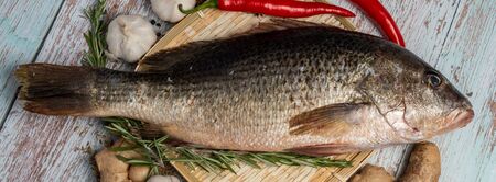 Fresh Fatty Fish on wooden table on wooden table Bass on rattan plate and wooden background