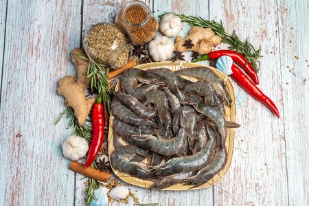 Fresh Tiger Prawns on a rattan plate surrounded by fresh raw ingredients.の写真素材