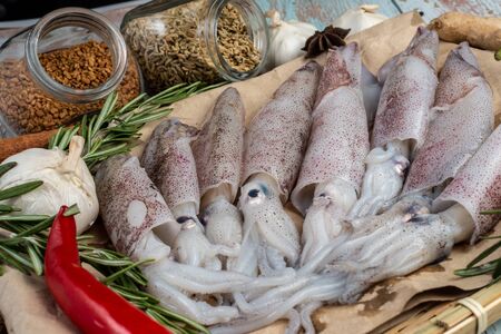 Fresh Raw Squids surrounded by spices and ingredient on a wooden tableの写真素材