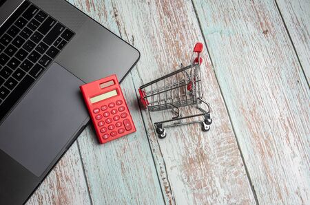 Laptop, calculator and shopping cart on wooden table. Online Shopping Concept.の写真素材