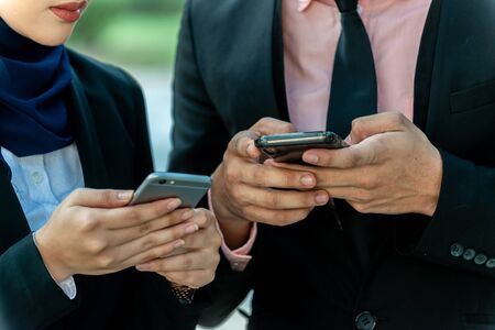 Muslim Couple on their smartphone. Texting and checking out their social mediaの写真素材