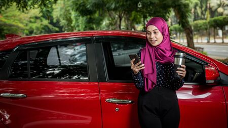 Muslim Female with her smartphone beside her car. Car insurance concept.の写真素材