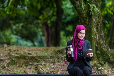 Muslim Businesswon on her table during a coffee break. Outdoor setting at a park.の写真素材