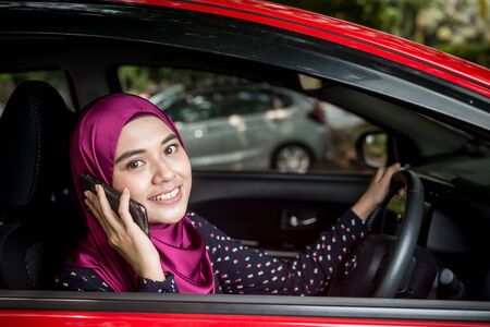 Muslim Female with her smartphone in her car. Car insurance concept.の写真素材
