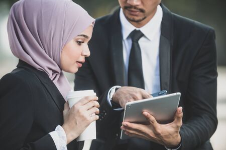 Muslim Businessman and businesswoman partner discussing using tablet connection social media for work. Outdoor Settingの写真素材