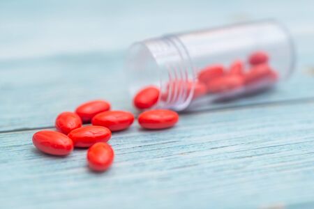 Red Colored Vitamins Pills on Wooden Background. Soft focused. Shallow depth of fieldの写真素材