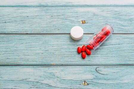 Red Colored Vitamins Pills on Wooden Background. Soft focused. Shallow depth of fieldの写真素材