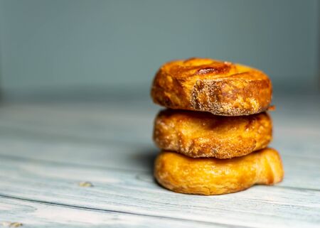 Stacked Homemade glazed puff pastry rolls on a  dark blue wooden background.  Shallow depth of field. Selective focusingの写真素材