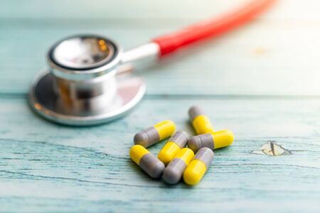 Pills with stethoscope on  wooden background. Shallow Depth of field.