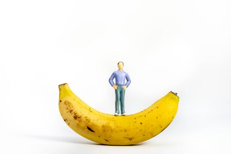 Yellow Banana and miniature models on White Background. Healthy lifestyle, fruit concept. Shallow depth of field, soft focusの写真素材