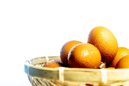 Fresh eggs with water condensation in a rattan basket. Isolated on white. Shallow depth of field.の写真素材