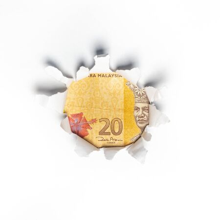 Ringgit Malaysia Currency through a ripped paper.