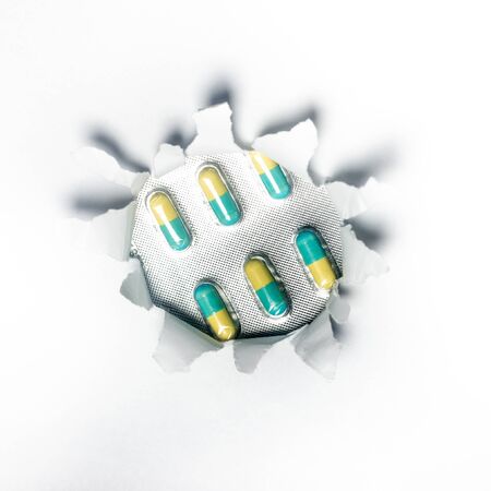 Drugs, Medicine, Pill through a ripped paper. Health concept.