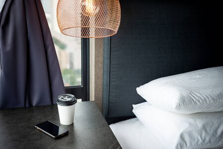 Coffee Cup To Go and a smartphone on the bedside. Technology and home concept.の写真素材