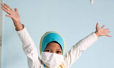 Muslim girl with hijab wearing surgical mask. Covid-19 and coronavirus concept. Shallow depth of fieldの写真素材