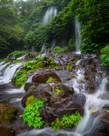 Lush Tropical Waterfall Flowing Through Green Jungle Landscapeの写真素材