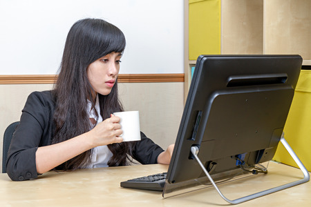 portrait of young businesswoman drinking coffee at desk looking tiredの写真素材