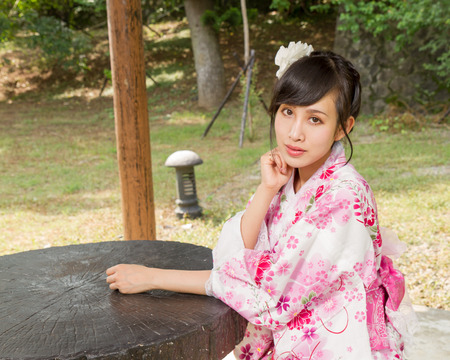 Asian woman in a kimono in a Japanese style gardenの写真素材