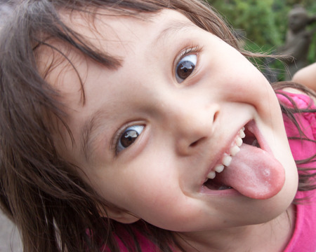 Child making funny face and sticking tongue outの写真素材