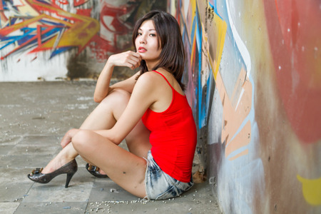 Beautiful Chinese woman sitting by graffiti wallsの写真素材