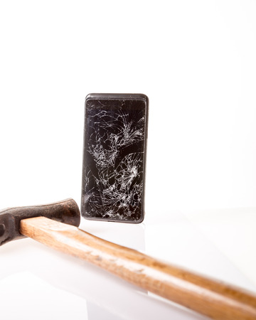 Mobile smartphone with broken screen with hammer next to it isolated on white.の写真素材