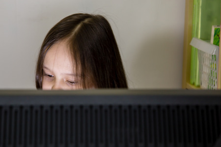 Young girl behind computer screenの写真素材