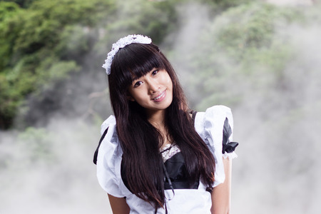 Chinese woman in maid outfit with steam in backgroundの写真素材
