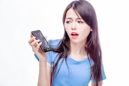 Asian woman looking at broken smartphone in disbeliefの写真素材
