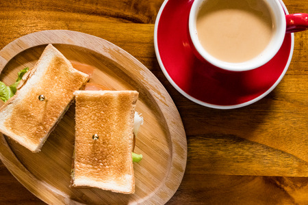 Coffee in red cup and saucer with toasted ham and cheese sandwich, top viewの写真素材
